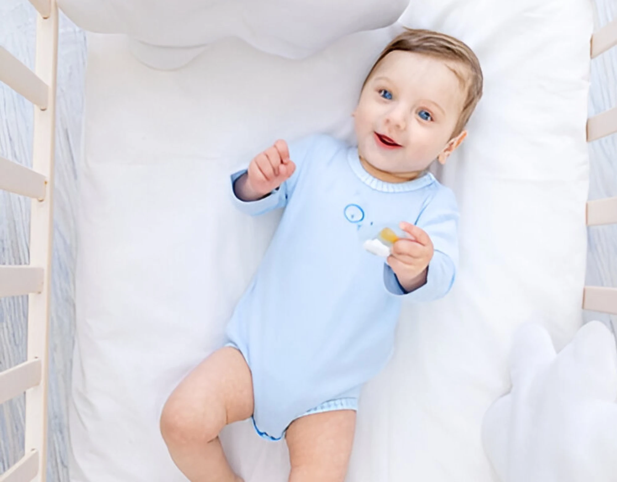 Smiling baby boy lying on premium soft kids bedding from Elite Kids Bedding